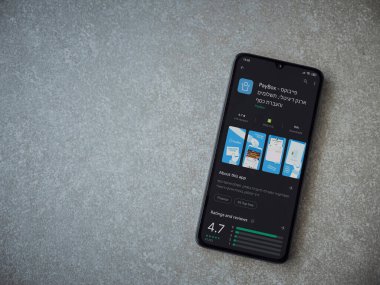 Lod, Israel - 8 Temmuz 2020: PayBox uygulaması oyun mağazası sayfası seramik taş zemin üzerinde siyah bir cep telefonu görüntüsü. Üst görünüm düzlüğü kopyalama alanı ile yatıyordu.