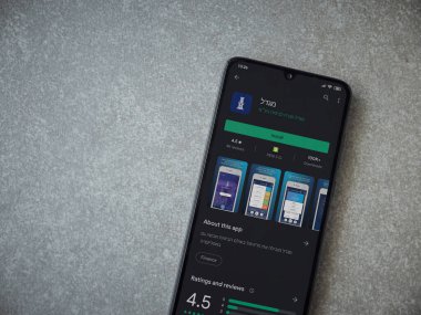 Lod, Israel - 8 Temmuz 2020: Migdal uygulaması oyun mağazası sayfası seramik taş zemin üzerinde siyah bir cep telefonu görüntüsü. Üst görünüm düzlüğü kopyalama alanı ile yatıyordu.