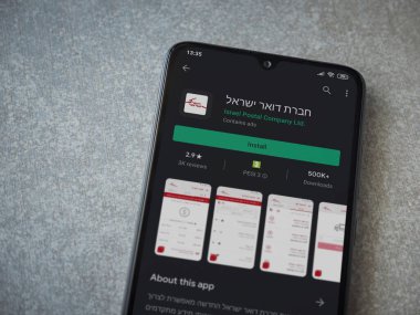 Lod, Israel - 8 Temmuz 2020: Israel Postal uygulama oyun mağazası sayfası seramik taş zemin üzerinde siyah bir cep telefonu sergilenmektedir. Üst görünüm düzlüğü kopyalama alanı ile yatıyordu.