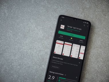 Lod, Israel - 8 Temmuz 2020: Israel Postal uygulama oyun mağazası sayfası seramik taş zemin üzerinde siyah bir cep telefonu sergilenmektedir. Üst görünüm düzlüğü kopyalama alanı ile yatıyordu.