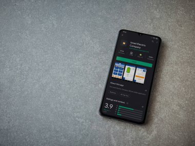 Lod, Israel - 8 Temmuz 2020: Israel Electric Corporation uygulama oyun mağazası sayfası seramik taş zemin üzerinde siyah bir cep telefonu görüntüsü. Üst görünüm düzlüğü kopyalama alanı ile yatıyordu.