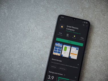 Lod, Israel - 8 Temmuz 2020: Israel Electric Corporation uygulama oyun mağazası sayfası seramik taş zemin üzerinde siyah bir cep telefonu görüntüsü. Üst görünüm düzlüğü kopyalama alanı ile yatıyordu.