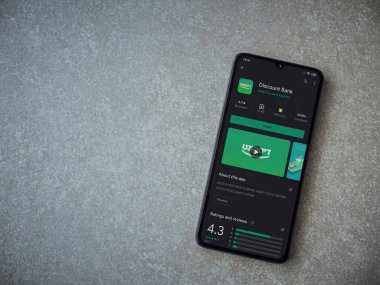 Lod, Israel - 8 Temmuz 2020: Banka İndirim uygulaması oyun mağazası sayfası seramik taş zemin üzerinde siyah bir cep telefonu görüntüsü. Üst görünüm düzlüğü kopyalama alanı ile yatıyordu.