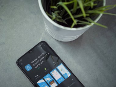 Lod, Israel - 8 Temmuz 2020: Mermer arka planda PayBox uygulaması oyun mağazası sayfası olan siyah cep telefonlu modern minimalist ofis çalışma alanı. Üst görünüm yatağını kapat.