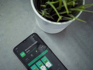 Lod, Israel - 8 Temmuz 2020: Mercantil İndirim uygulaması oyun sayfası mermer arka planda siyah cep telefonlu modern minimalist ofis çalışma alanı. Üst görünüm yatağını kapat.