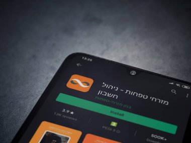 Lod, Israel - 8 Temmuz 2020: Bank Mizrahi Tefahot uygulaması oyun mağazası sayfası koyu mermer taştan arka planda siyah bir cep telefonu sergilenmektedir. Üst görünüm düzlüğü kopyalama alanı ile yatıyordu.