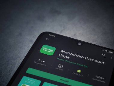 Lod, Israel - 8 Temmuz 2020: Bank Mercantil Discount uygulaması oyun mağazası sayfası koyu mermer taşlı arka planda siyah bir cep telefonu sergilenmektedir. Üst görünüm düzlüğü kopyalama alanı ile yatıyordu.