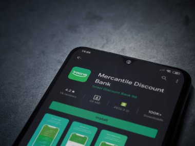Lod, Israel - 8 Temmuz 2020: Bank Mercantil Discount uygulaması oyun mağazası sayfası koyu mermer taşlı arka planda siyah bir cep telefonu sergilenmektedir. Üst görünüm düzlüğü kopyalama alanı ile yatıyordu.