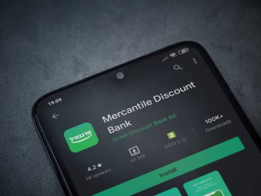 Lod, Israel - 8 Temmuz 2020: Bank Mercantil Discount uygulaması oyun mağazası sayfası koyu mermer taşlı arka planda siyah bir cep telefonu sergilenmektedir. Üst görünüm düzlüğü kopyalama alanı ile yatıyordu.