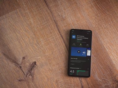 Lod, Israel - 8 Temmuz 2020: XE Para Birimi uygulaması oyun mağazası sayfası ahşap arka planda siyah bir cep telefonunun ekranında. Üst görünüm düzlüğü kopyalama alanı ile yatıyordu.