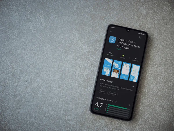 Lod, Israel - 8 Temmuz 2020: PayBox uygulaması oyun mağazası sayfası seramik taş zemin üzerinde siyah bir cep telefonu görüntüsü. Üst görünüm düzlüğü kopyalama alanı ile yatıyordu.