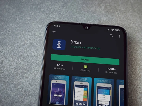 Lod, Israel - 8 Temmuz 2020: Migdal uygulaması oyun mağazası sayfası seramik taş zemin üzerinde siyah bir cep telefonu görüntüsü. Üst görünüm düzlüğü kopyalama alanı ile yatıyordu.