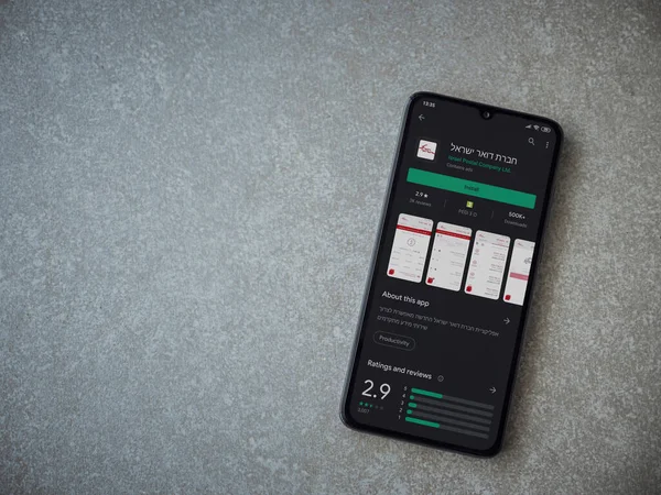 Lod, Israel - 8 Temmuz 2020: Israel Postal uygulama oyun mağazası sayfası seramik taş zemin üzerinde siyah bir cep telefonu sergilenmektedir. Üst görünüm düzlüğü kopyalama alanı ile yatıyordu.