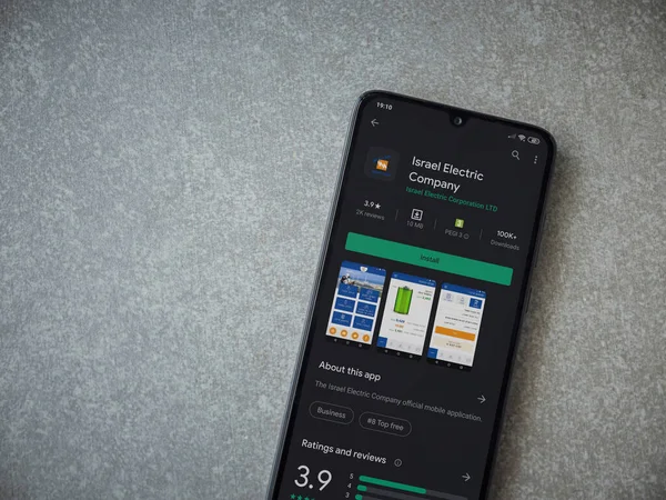 Lod, Israel - 8 Temmuz 2020: Israel Electric Corporation uygulama oyun mağazası sayfası seramik taş zemin üzerinde siyah bir cep telefonu görüntüsü. Üst görünüm düzlüğü kopyalama alanı ile yatıyordu.