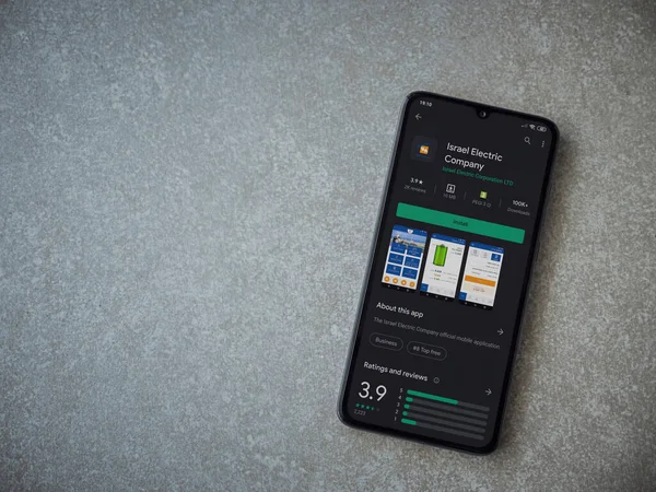 Lod, Israel - 8 Temmuz 2020: Israel Electric Corporation uygulama oyun mağazası sayfası seramik taş zemin üzerinde siyah bir cep telefonu görüntüsü. Üst görünüm düzlüğü kopyalama alanı ile yatıyordu.