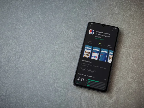 Lod, Israel - 8 Temmuz 2020: Isracard uygulama oyun mağazası sayfası seramik taş zemin üzerinde siyah bir cep telefonu ekranında. Üst görünüm düzlüğü kopyalama alanı ile yatıyordu.