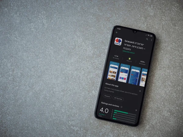 Lod, Israel - 8 Temmuz 2020: Isracard uygulama oyun mağazası sayfası seramik taş zemin üzerinde siyah bir cep telefonu ekranında. Üst görünüm düzlüğü kopyalama alanı ile yatıyordu.