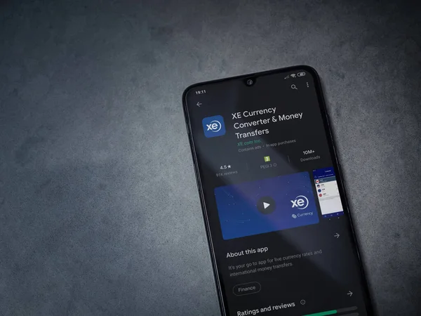 Lod, Israel - 8 Temmuz 2020: XE Para Birimi uygulaması oyun mağazası sayfası koyu mermer taştan arka planda siyah bir cep telefonu görüntüsü. Üst görünüm düzlüğü kopyalama alanı ile yatıyordu.