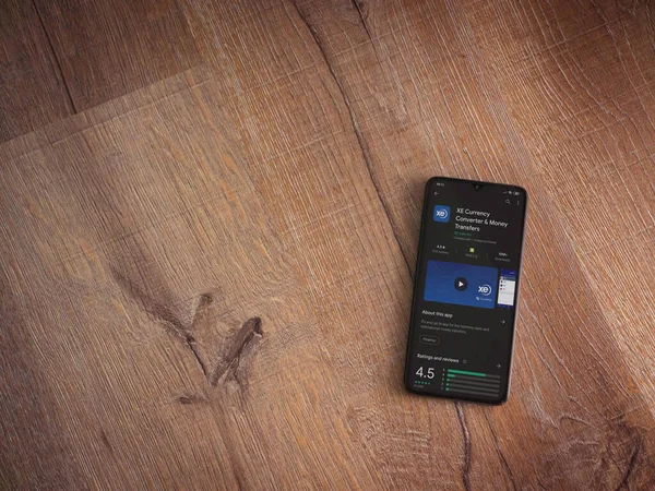 Lod, Israel - 8 Temmuz 2020: XE Para Birimi uygulaması oyun mağazası sayfası ahşap arka planda siyah bir cep telefonunun ekranında. Üst görünüm düzlüğü kopyalama alanı ile yatıyordu.
