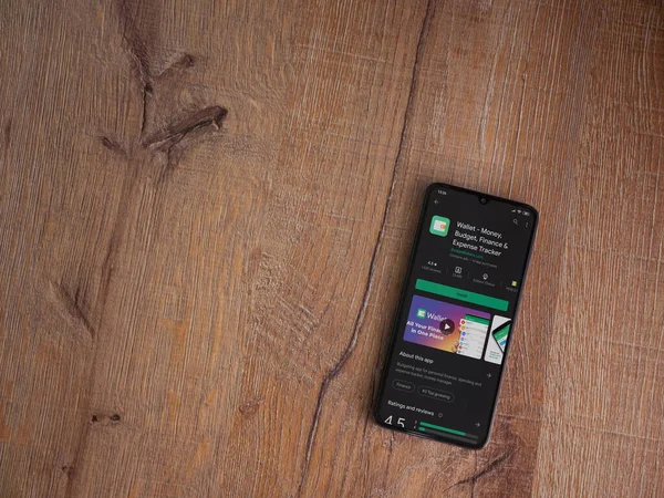 Lod, Israel - 8 Temmuz 2020: Cüzdan uygulaması oyun mağazası sayfası ahşap arka planda siyah bir cep telefonu ekranında. Üst görünüm düzlüğü kopyalama alanı ile yatıyordu.