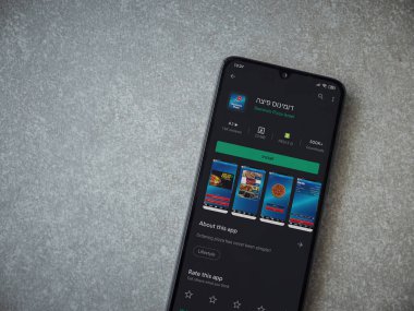 Lod, Israel - 8 Temmuz 2020: Domino 'nun Pizza Israel uygulaması oyun mağazası sayfası seramik taş zemin üzerinde siyah bir cep telefonunun görüntüsü. Üst görünüm düzlüğü kopyalama alanı ile yatıyordu.