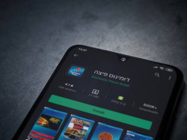 Lod, Israel - 8 Temmuz 2020: Domino 'nun Pizza Israel uygulaması oyun mağazası sayfası koyu mermer taşlı arka planda siyah bir cep telefonunun ekranında. Üst görünüm düzlüğü kopyalama alanı ile yatıyordu.