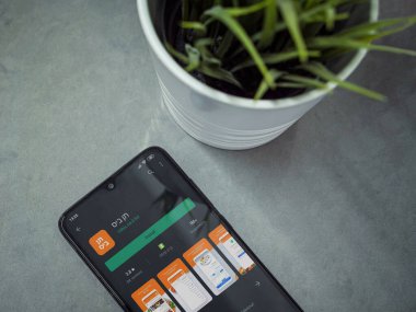 Lod, Israel - 8 Temmuz 2020: Mermer zemin üzerinde 10bis uygulamalı oyun mağazası sayfası olan siyah cep telefonlu modern minimalist ofis çalışma alanı. Üst görünüm yatağını kapat.