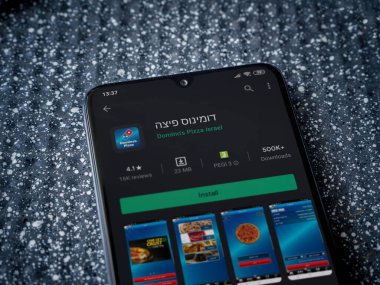 Lod, Israel - 8 Temmuz 2020: Domino 'nun Pizza Israel uygulama oyun mağazası sayfası metalik arka planda siyah bir cep telefonunun ekranında. Üst görünüm yatağını kapat.