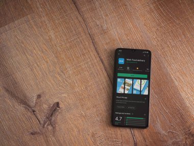 Lod, Israel - 8 Temmuz 2020: Wolt uygulama oyun mağazası sayfası ahşap arka planda siyah bir cep telefonunun ekranında. Üst görünüm düzlüğü kopyalama alanı ile yatıyordu.