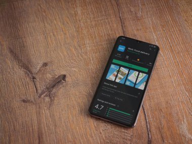 Lod, Israel - 8 Temmuz 2020: Wolt uygulama oyun mağazası sayfası ahşap arka planda siyah bir cep telefonunun ekranında. Üst görünüm düzlüğü kopyalama alanı ile yatıyordu.