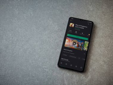 Lod, Israel - 8 Temmuz 2020: Krallığın Yükselişi uygulaması oyun mağazası sayfasında seramik taş zemin üzerinde siyah bir cep telefonu görüntüsü. Üst görünüm düzlüğü kopyalama alanı ile yatıyordu.