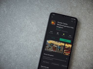 Lod, Israel - 8 Temmuz 2020: Hustle Castle uygulaması oyun mağazası sayfası seramik taş zemin üzerinde siyah bir cep telefonu görüntüsü. Üst görünüm düzlüğü kopyalama alanı ile yatıyordu.