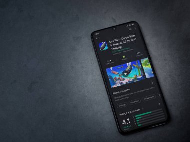 Lod, Israel - 8 Temmuz 2020: Deniz Limanı uygulaması oyun mağazası sayfası koyu mermer taştan arka planda siyah bir cep telefonu sergilenmektedir. Üst görünüm düzlüğü kopyalama alanı ile yatıyordu.