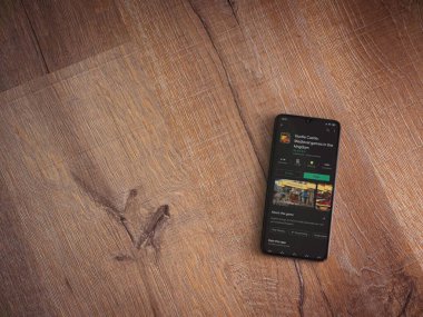 Lod, Israel - 8 Temmuz 2020: Hustle Castle uygulama oyun mağazası sayfası ahşap arka planda siyah bir cep telefonunun ekranında. Üst görünüm düzlüğü kopyalama alanı ile yatıyordu.