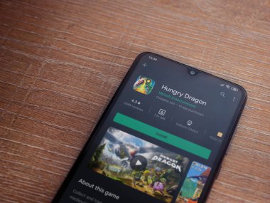Lod, Israel - 8 Temmuz 2020: Aç Ejderha uygulaması oyun mağazası sayfası ahşap arka planda siyah bir cep telefonunun ekranında. Üst görünüm düzlüğü kopyalama alanı ile yatıyordu.