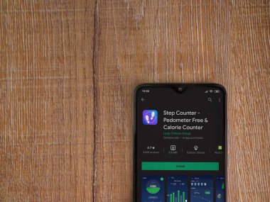 Lod, Israel - 8 Temmuz 2020: Step Counter uygulama oyun mağazası sayfası ahşap arka planda siyah bir cep telefonunun ekranında. Üst görünüm düzlüğü kopyalama alanı ile yatıyordu.