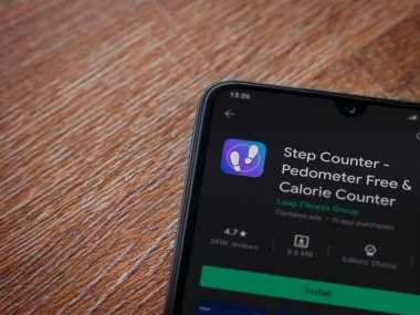 Lod, Israel - 8 Temmuz 2020: Step Counter uygulama oyun mağazası sayfası ahşap arka planda siyah bir cep telefonunun ekranında. Üst görünüm düzlüğü kopyalama alanı ile yatıyordu.