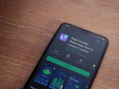 Lod, Israel - 8 Temmuz 2020: Step Counter uygulama oyun mağazası sayfası ahşap arka planda siyah bir cep telefonunun ekranında. Üst görünüm düzlüğü kopyalama alanı ile yatıyordu.