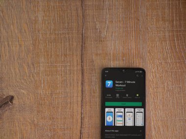 Lod, Israel - 8 Temmuz 2020: Ahşap arka planda siyah bir cep telefonunun ekranında yedi uygulama mağaza sayfası. Üst görünüm düzlüğü kopyalama alanı ile yatıyordu.