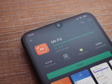 Lod, Israel - 8 Temmuz 2020: Mi Fit uygulaması oyun mağazası sayfası ahşap arka planda siyah bir cep telefonunun ekranında. Üst görünüm düzlüğü kopyalama alanı ile yatıyordu.