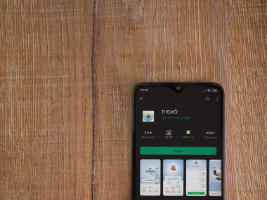 Lod, Israel - 8 Temmuz 2020: Leumit Health Services uygulama oyun mağazası sayfası ahşap arka planda siyah bir cep telefonu sergilenmektedir. Üst görünüm düzlüğü kopyalama alanı ile yatıyordu.