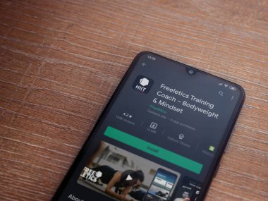 Lod, Israel - 8 Temmuz 2020: Freeletics Eğitim Koçu uygulama oyun mağazası sayfası ahşap arka planda siyah bir cep telefonunun ekranında. Üst görünüm düzlüğü kopyalama alanı ile yatıyordu.