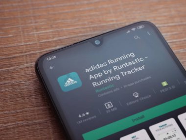 Lod, Israel - 8 Temmuz 2020: Adidas Running app playshop sayfası ahşap arka planda siyah bir cep telefonunun ekranında. Üst görünüm düzlüğü kopyalama alanı ile yatıyordu.