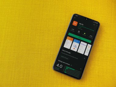 Lod, Israel - 8 Temmuz 2020: Mi Fit uygulama oyun mağazası sayfası sarı kumaş arka planda siyah bir cep telefonunun ekranında. Üst görünüm düzlüğü kopyalama alanı ile yatıyordu.