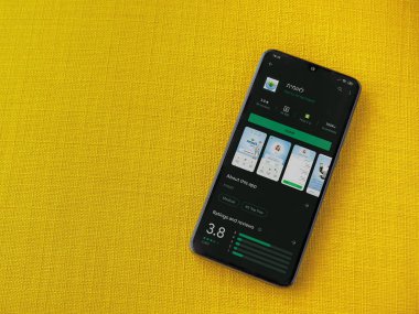 Lod, Israel - 8 Temmuz 2020: Leumit Health Services uygulama oyun mağazası sayfası sarı kumaş arka planda siyah bir cep telefonu sergilenmektedir. Üst görünüm düzlüğü kopyalama alanı ile yatıyordu.
