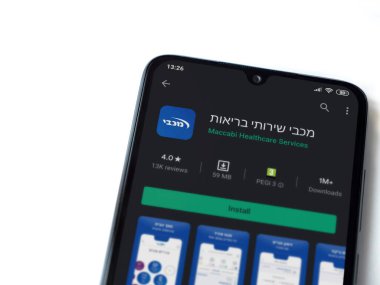 Lod, Israel - 8 Temmuz 2020: Maccbi Sağlık Hizmetleri uygulama oyun mağazası sayfası beyaz arkaplanda izole edilmiş siyah bir cep telefonu ekranında. Üst görünüm düzlüğü kopyalama alanı ile yatıyordu.