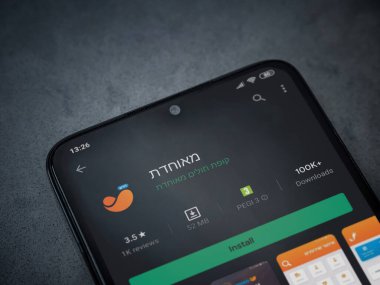 Lod, Israel - 8 Temmuz 2020: Meuhedet Sağlık Hizmetleri uygulama oyun mağazası sayfası koyu mermer taşlı arka planda siyah bir cep telefonu sergilenmektedir. Üst görünüm düzlüğü kopyalama alanı ile yatıyordu.