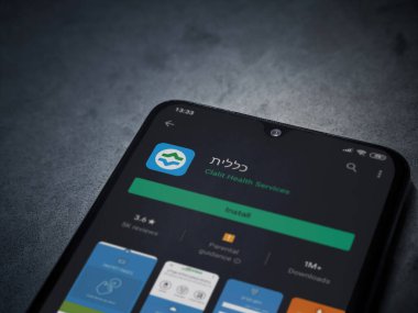 Lod, Israel - 8 Temmuz 2020: Clalit Sağlık Hizmetleri uygulama oyun mağazası sayfası koyu mermer taşlı arka planda siyah bir cep telefonu sergilenmektedir. Üst görünüm düzlüğü kopyalama alanı ile yatıyordu.