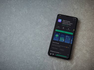 Lod, Israel - 8 Temmuz 2020: Step Counter uygulaması oyun mağazası sayfasında seramik taş zemin üzerinde siyah bir cep telefonu görüntüsü. Üst görünüm düzlüğü kopyalama alanı ile yatıyordu.