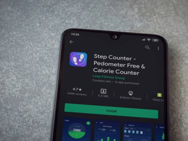 Lod, Israel - 8 Temmuz 2020: Step Counter uygulaması oyun mağazası sayfasında seramik taş zemin üzerinde siyah bir cep telefonu görüntüsü. Üst görünüm düzlüğü kopyalama alanı ile yatıyordu.